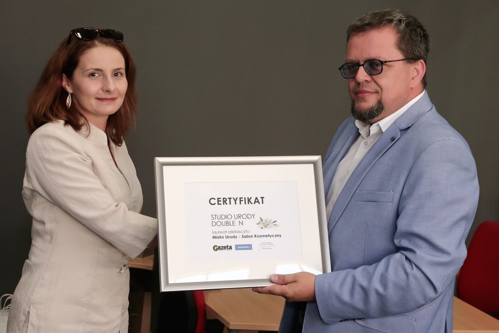 O nas - Justyna Neumann właściciel Double N odbiera certyfikat "Mistrz Urody" od Pawła Relikowskiego z Polska Press